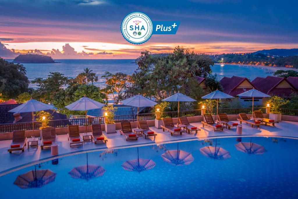 una piscina de hotel con sillas y sombrillas por la noche en Chanalai Garden Resort, Kata Beach en Kata Beach