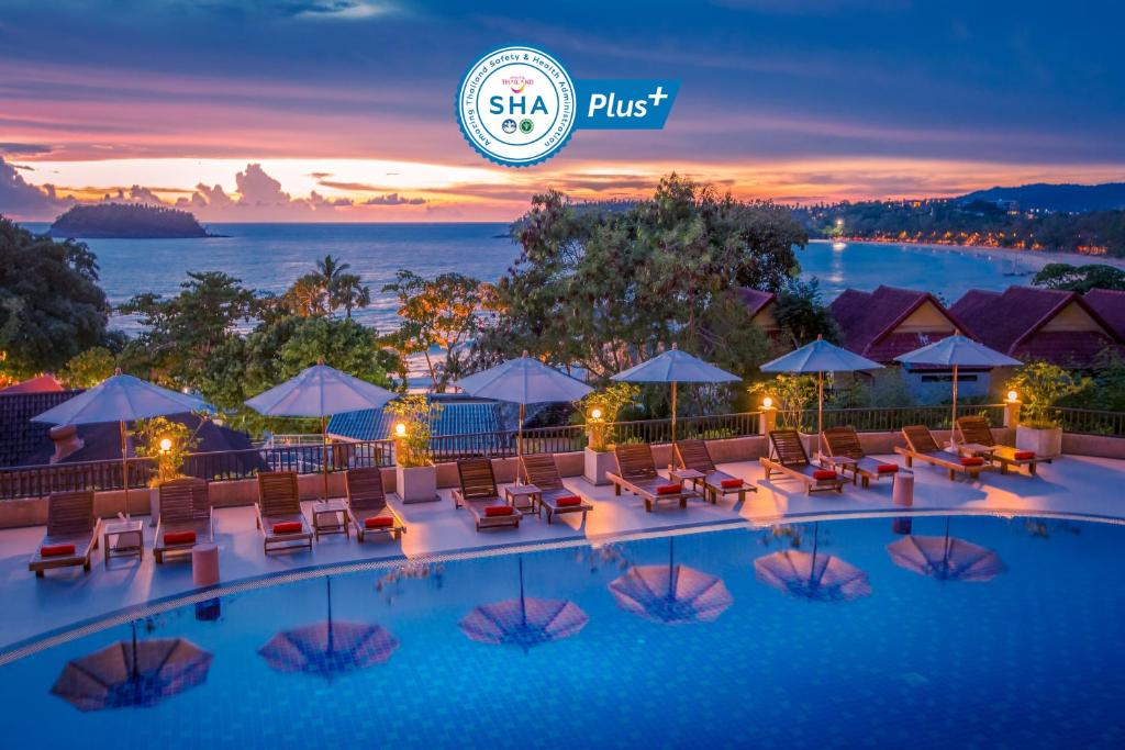 Chanalai Garden Resort, Kata Beach في شاطئ كاتا: مسبح الفندق مع الكراسي والمظلات في الليل