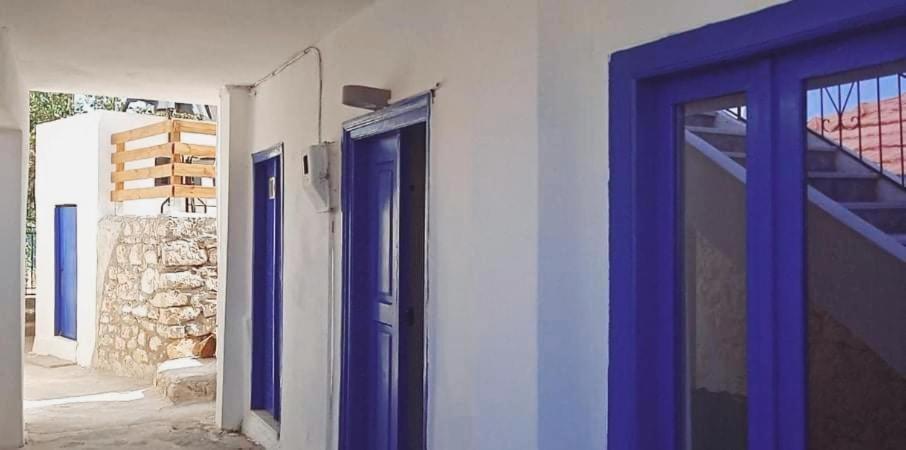 a blue door on a white building with a window at Occasus Room Comfort in Halki