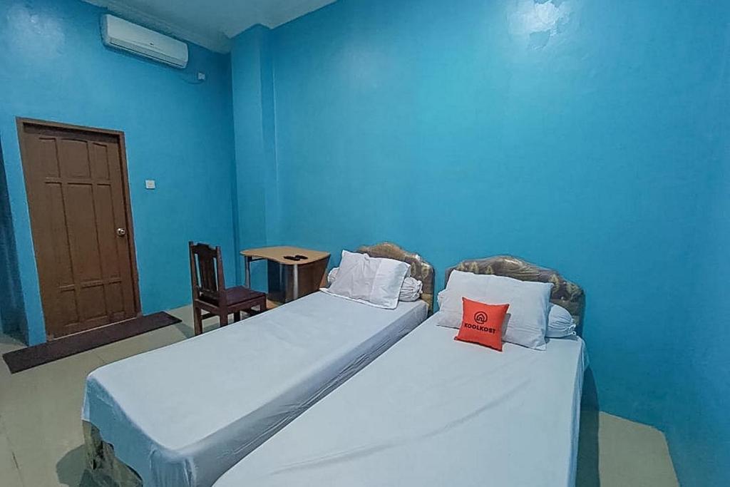 a blue room with two beds with pillows on them at KoolKost Syariah At Komplek PLN Balikpapan in Balikpapan