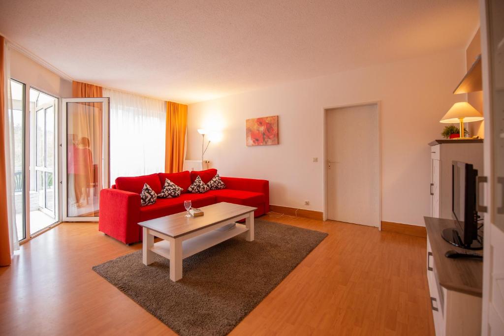 Sala de estar con sofá rojo y mesa de centro en Ferienwohnung Sanddorn - Strandhaus Lobbe, en Lobbe