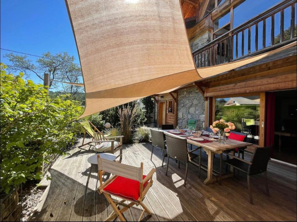 une terrasse avec une table et des chaises en bois dans l'établissement Chez La Nanie, à Saint-Paul-en-Chablais