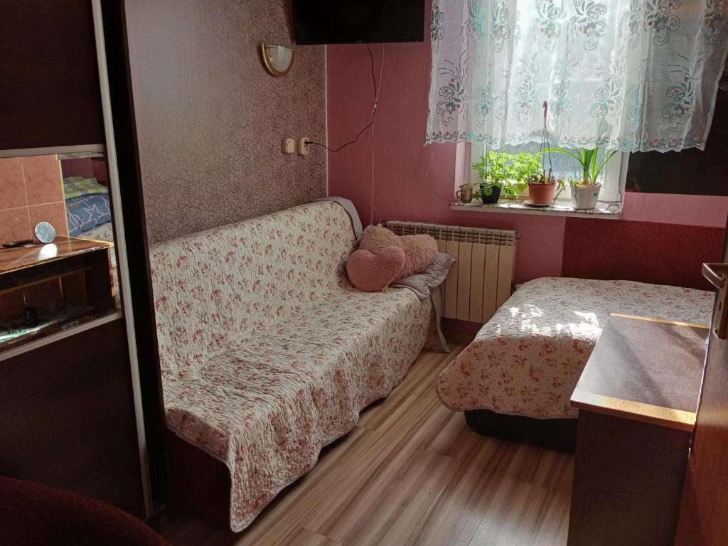 a small room with a couch and a bed and a window at Pokoje u Adama i Ewy in Szczawnica