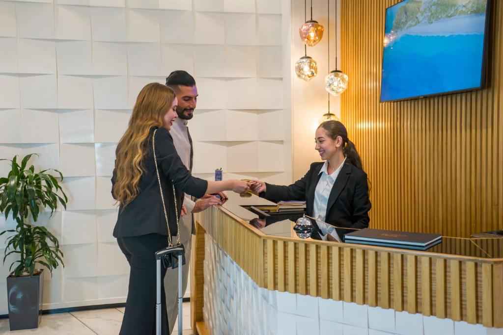 un uomo e una donna che stringono la mano a un bancone di Flamant Rose Appart Hotel a Tangeri