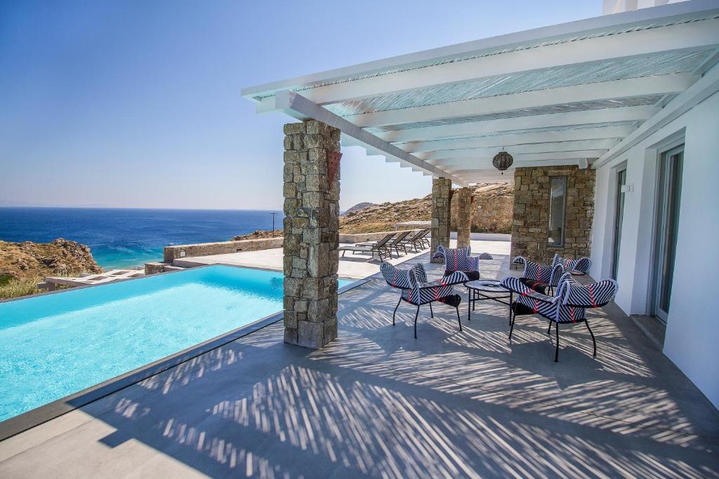 un patio con tavolo, sedie e piscina di Anarina Villas & Suites Mykonos Elia Beach a Elia Beach