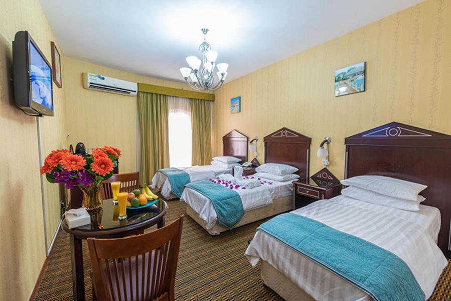 a hotel room with two beds and a table at Victoria Hotel in Dubai