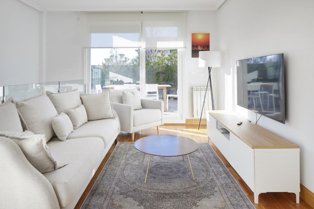 a living room with a white couch and a tv at Esnatuz - Basque Stay in San Sebastián