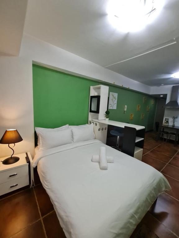 a bedroom with a white bed and a green wall at Solemare Parksuites Condominium - Condo R Us in Manila