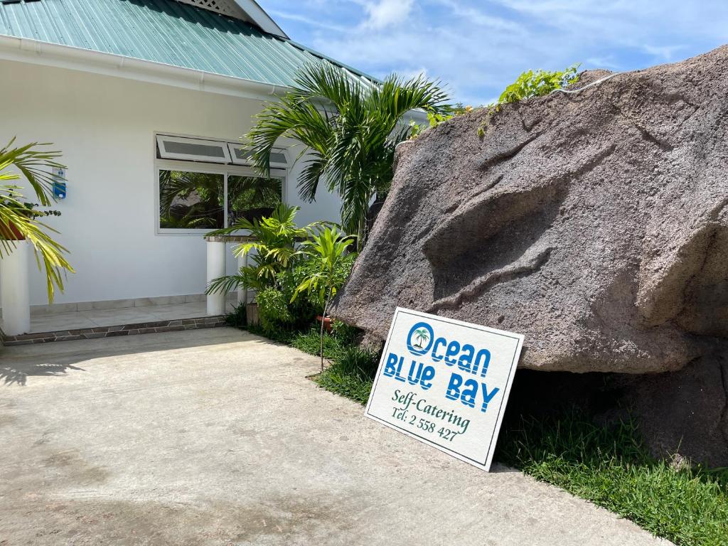 a sign in front of a house with a big rock at Ocean Blue Bay in Anse Volbert Village