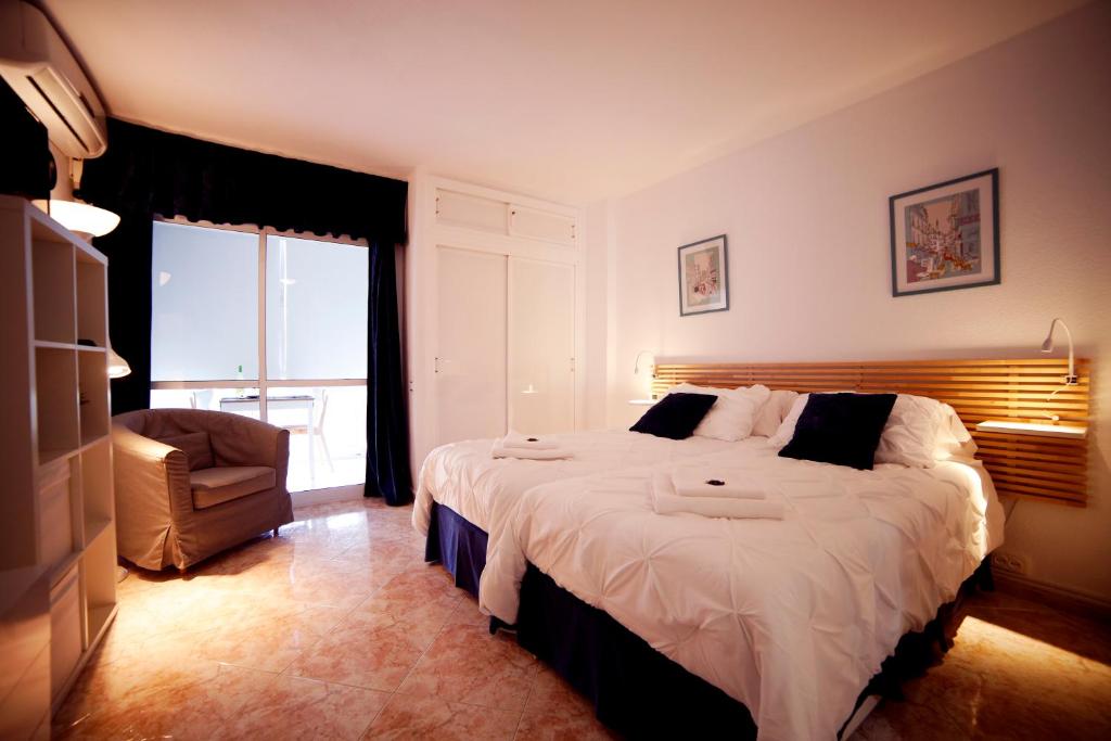 a bedroom with a large bed and a chair at Apartamentos DC in Benalmádena