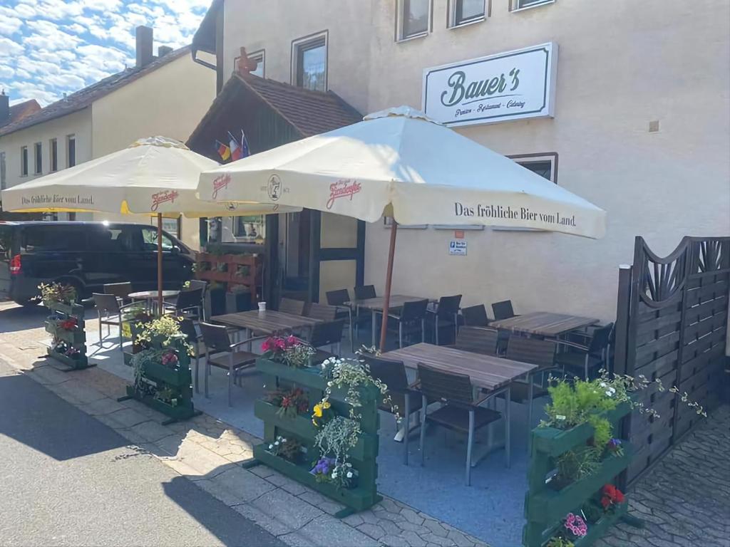 a restaurant with tables and umbrellas in front of a building at Bauer´s Pension-Restaurant-Catering in Großhabersdorf