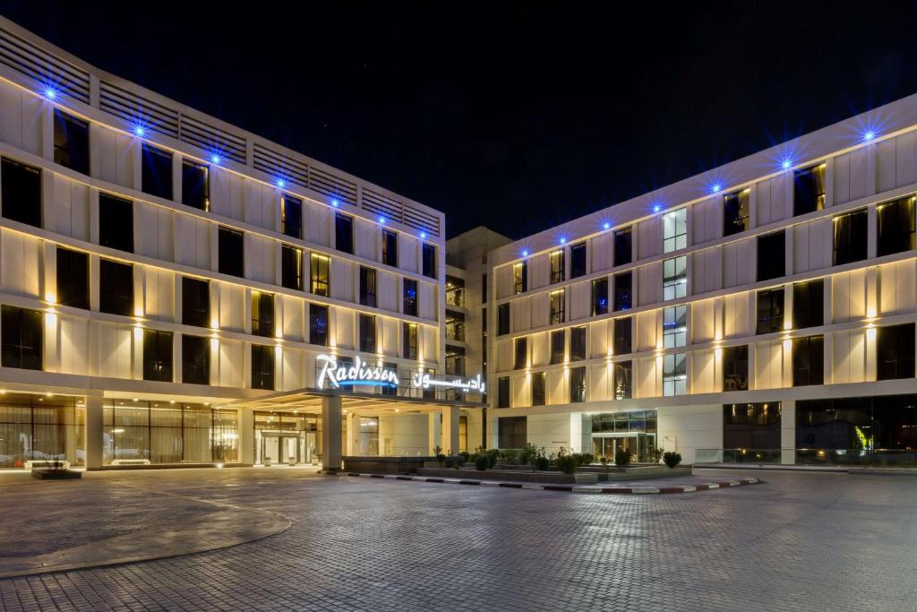 a hotel with a parking lot in front of it at Radisson Hotel & Apartments Dammam Industry City in Dammam