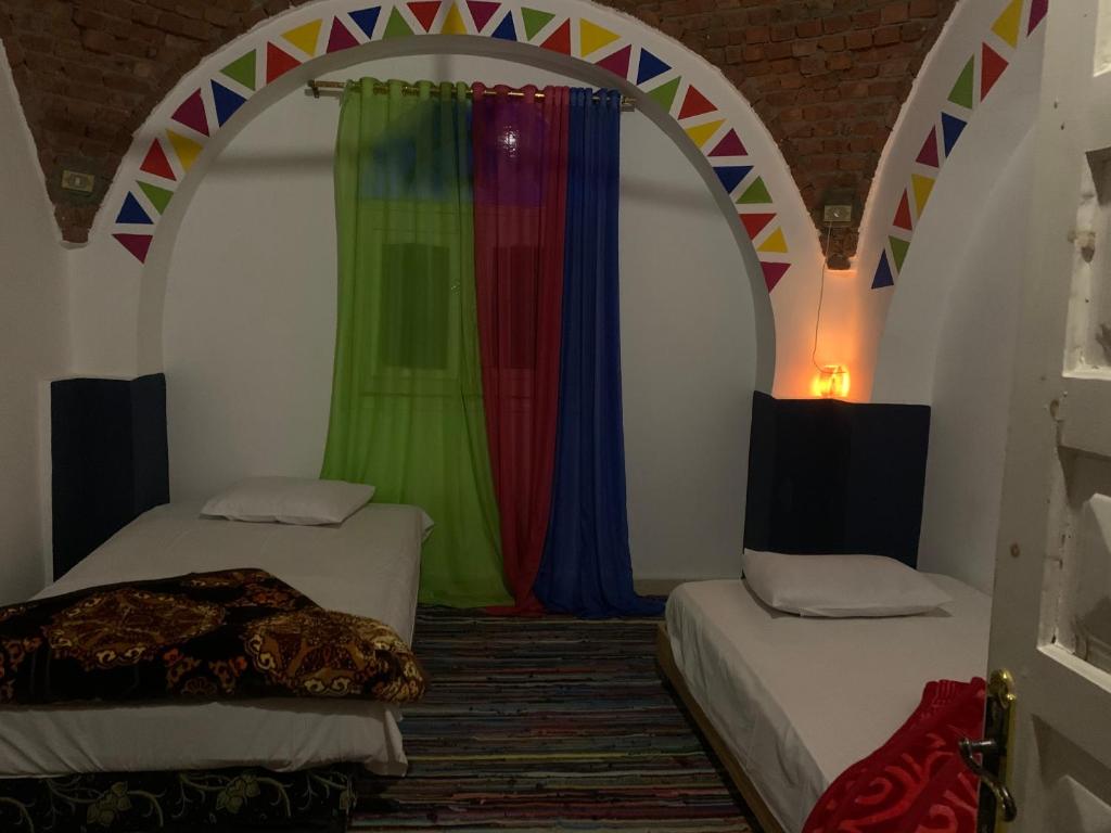 a room with two beds and a colorful curtain at Nubian Farm Aswan in Aswan