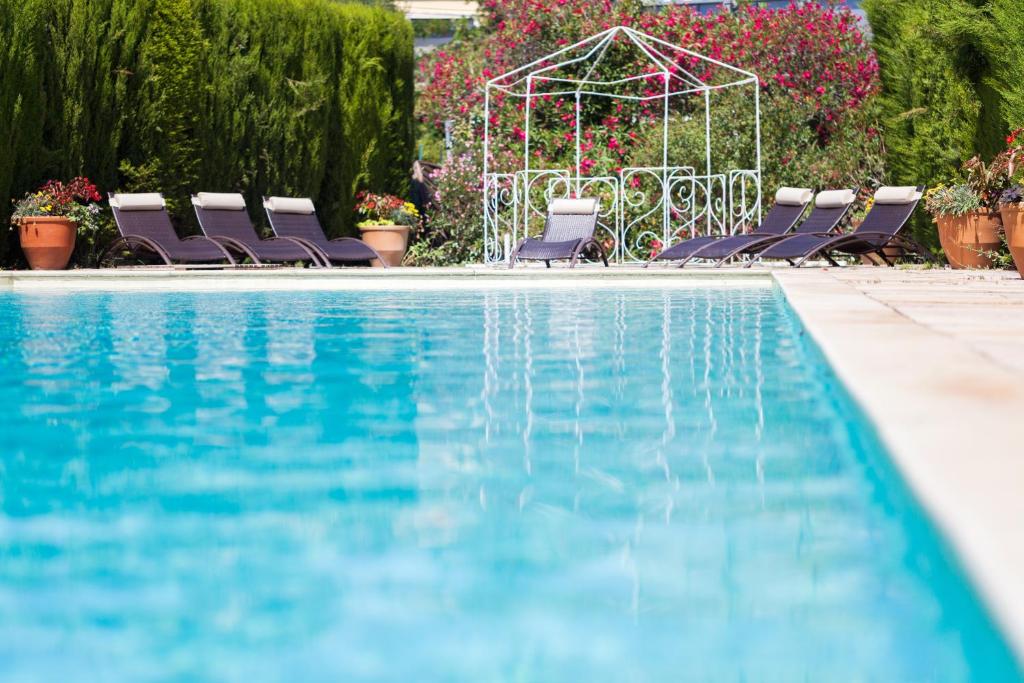 - une piscine avec des chaises et un kiosque dans l'établissement Logis VIGNES BLANCHES*** Hôtel Cosy et restaurant de terroir, à Beaucaire