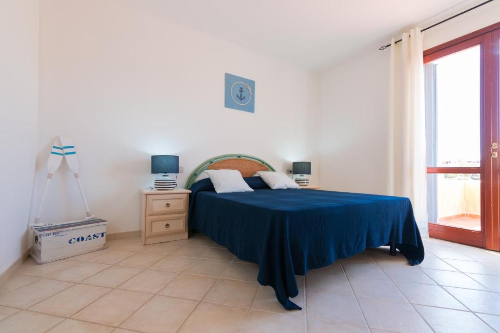 a bedroom with a bed with a blue blanket on it at SardegnaSummer Il Borgo Porto San Paolo in Porto San Paolo