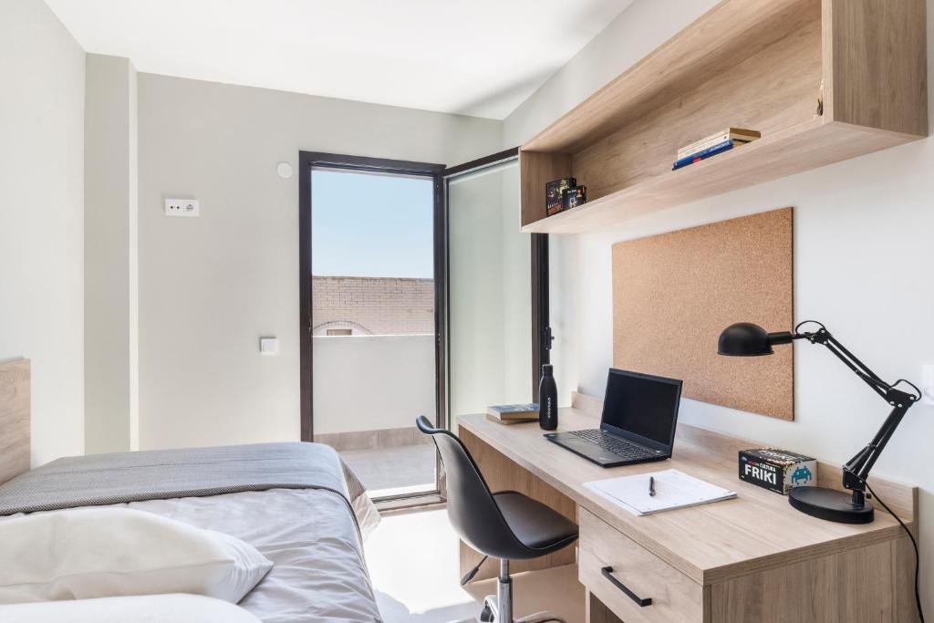 um quarto com uma cama e uma secretária com um computador portátil em Micampus Cartagena em Cartagena