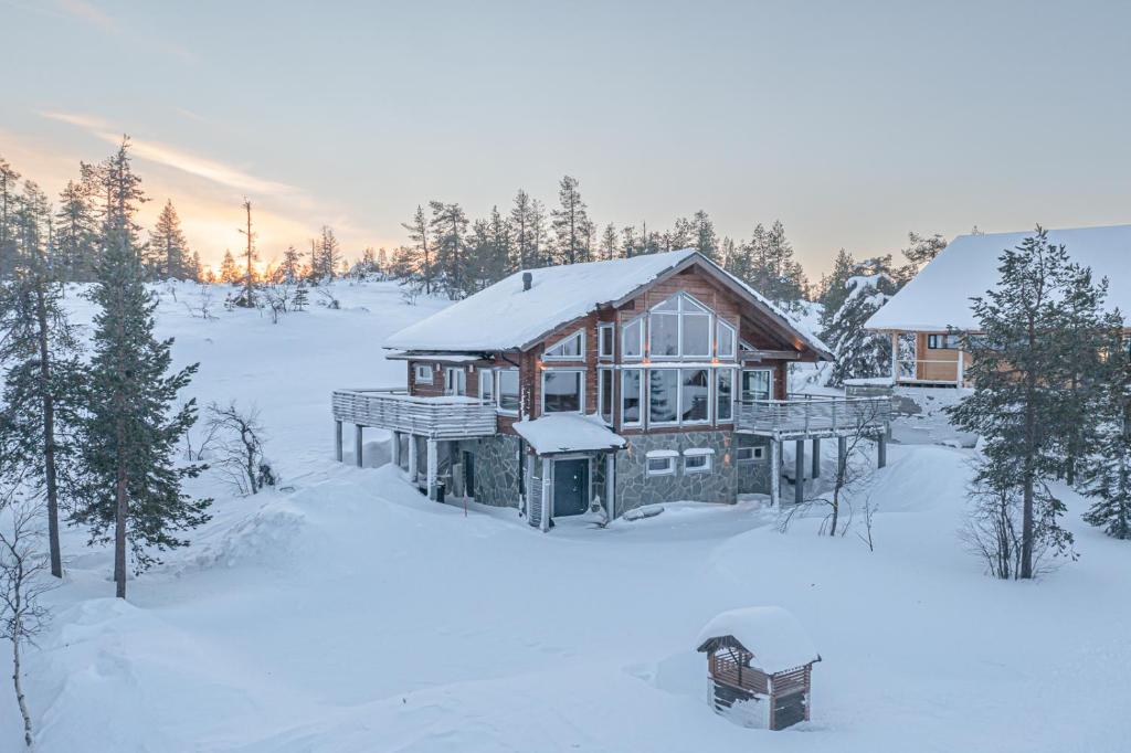 Una cabaña de madera en la nieve con nieve. en Levillas Kinnastie 35 Villas, en Levi