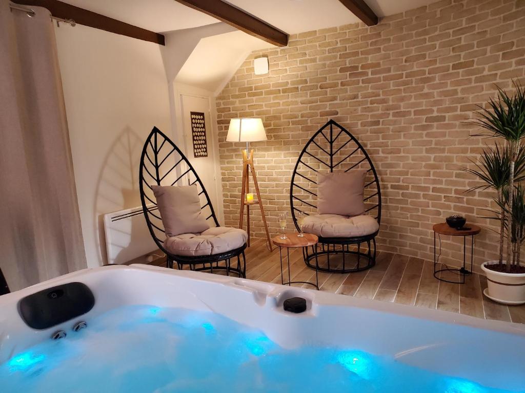 a bathroom with a tub and two chairs in a room at Jacuzzi privatif dans maison de village au calme in Flaviac