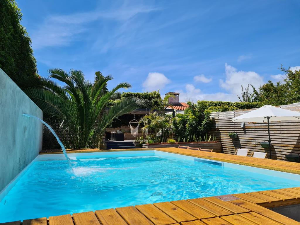 a swimming pool in a backyard with a wooden deck at Casa do Contador - Suites & Pool in Ponta Delgada