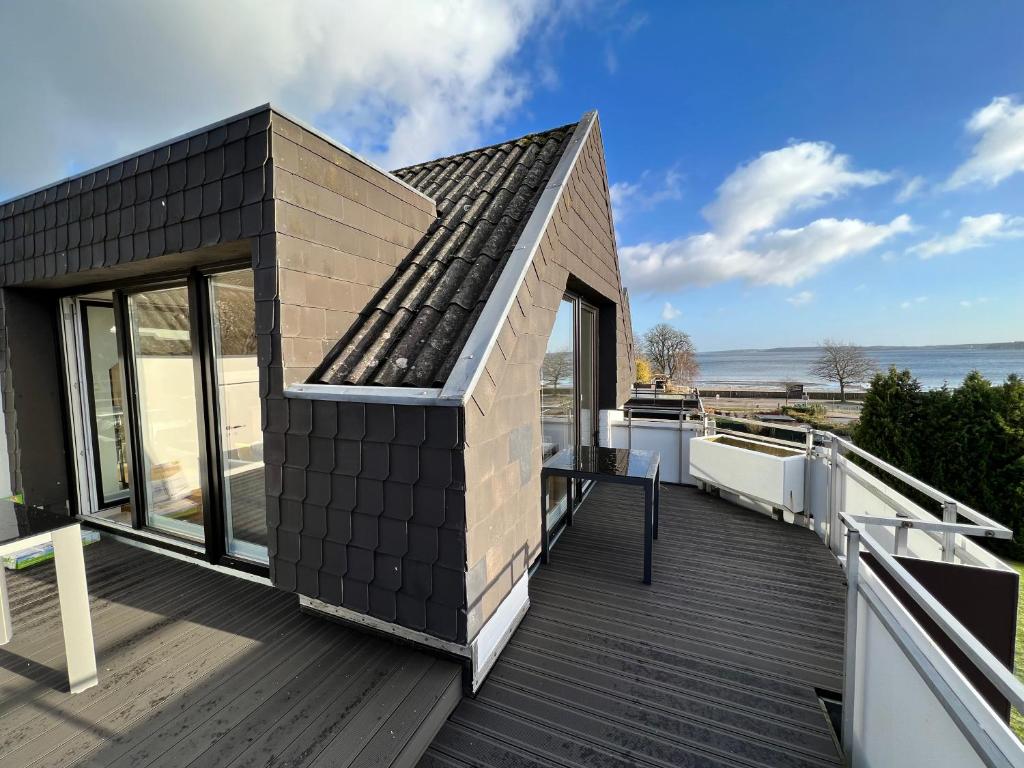 uma pequena casa com um telhado preto num deque em BEACH HOUSE II - Penthousewohnung in Bestlage mit sonniger Dachterrasse und top Meerblick em Harrislee