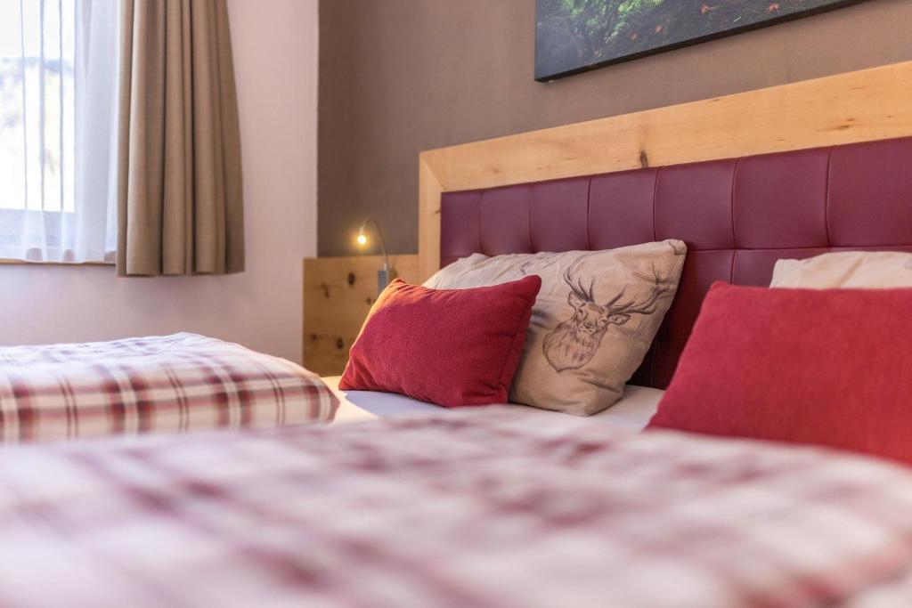 a bedroom with two beds with red pillows at Ciasa Rungg App Corones in San Vigilio Di Marebbe