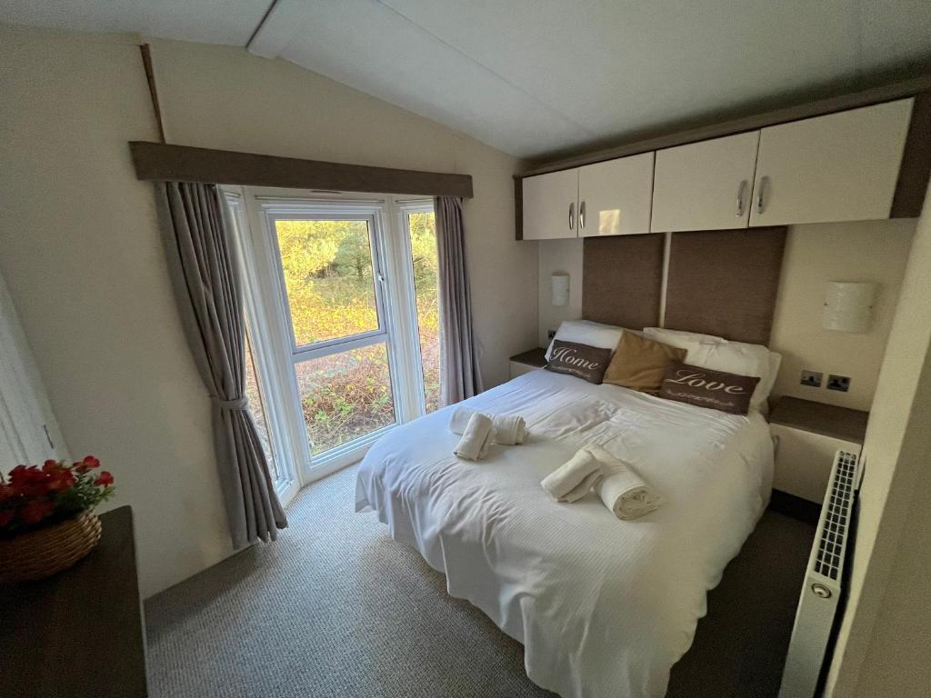 1 dormitorio con 1 cama con toallas en Hazel Oaks, Beautiful Lodge with Hot Tub - Sleeps 6 - Felmoor Park, en Morpeth