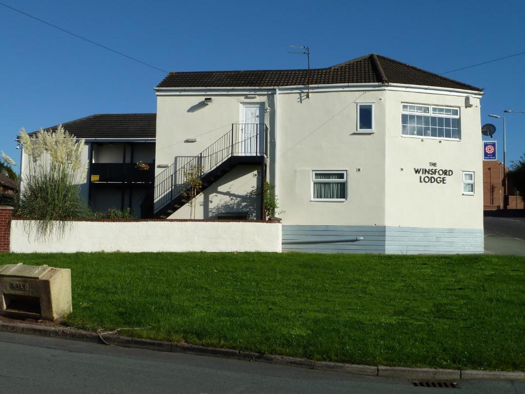 Una casa blanca con una escalera negra. en The Winsford Lodge, en Winsford