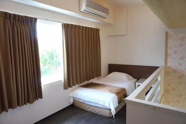 a small bedroom with a bed and a window at River Forest Leisure Farm in Dongshan