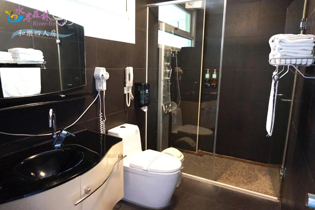 a bathroom with a sink and a shower and a toilet at River Forest Leisure Farm in Dongshan