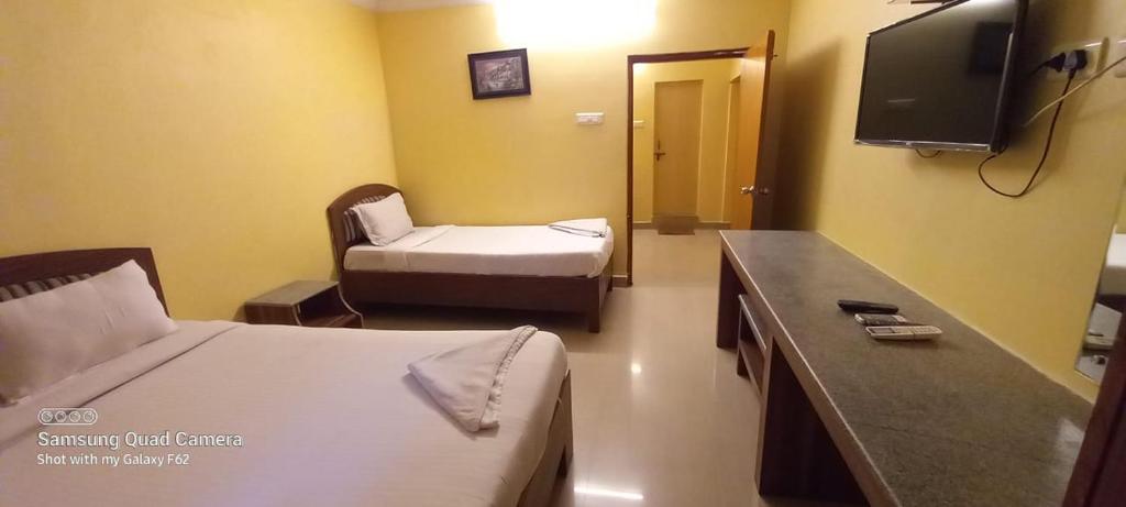 um quarto de hotel com duas camas e uma televisão em Royal Stay em Visakhapatnam