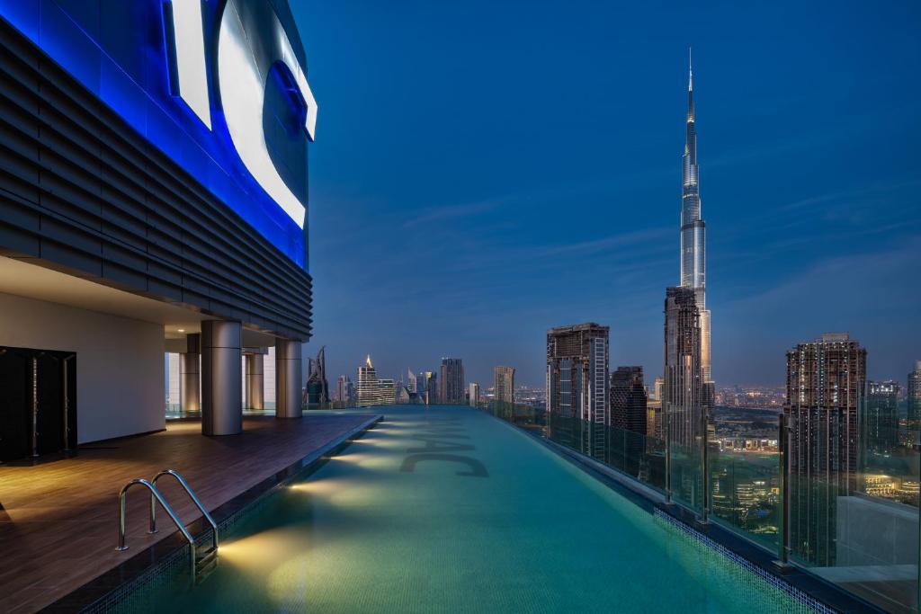 a swimming pool on the roof of a building with a city skyline at Paramount Hotel Midtown in Dubai