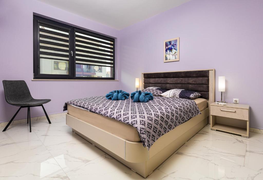 a bedroom with a bed and a chair and a window at The Purple 1DB Apartment with a Parking Spot in Plovdiv