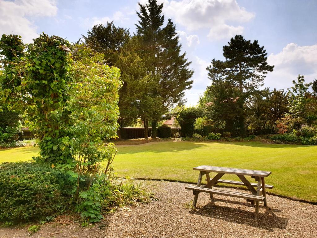 una mesa de picnic de madera en un parque con un campo en The Crown House Inn en Great Chesterford