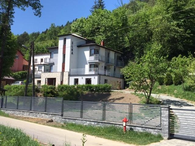 a large white house with a fence in front of it at Willa Elka in Muszyna