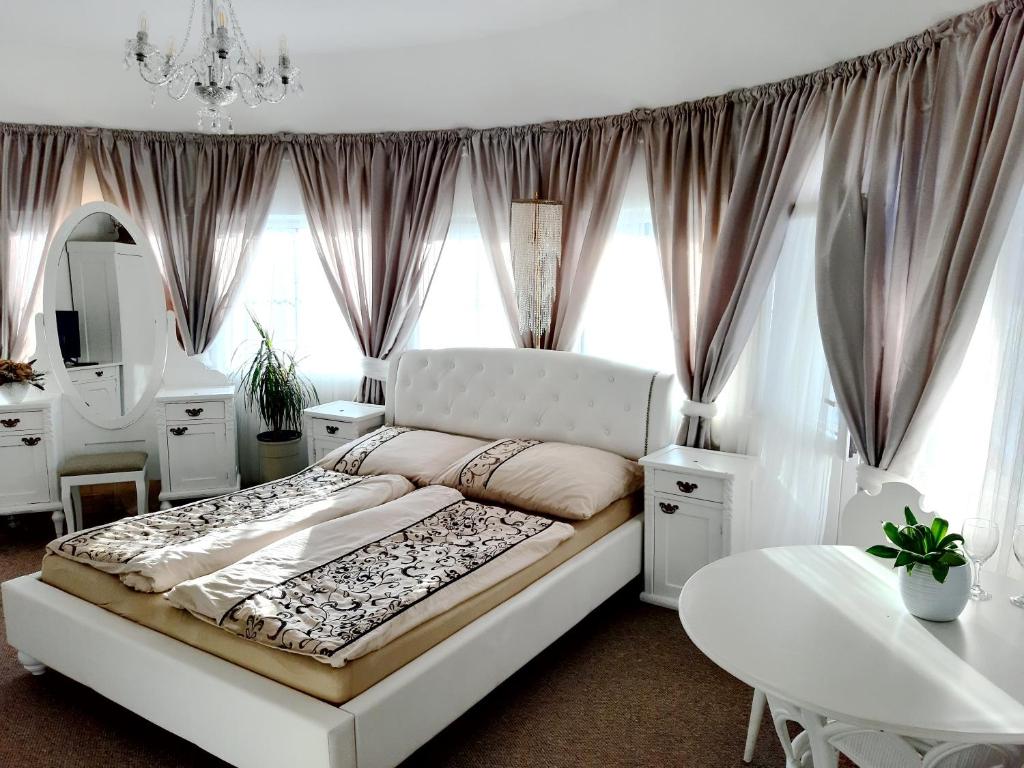 a bedroom with a large white bed and a table at Penzion a Restaurace Belveder in Jáchymov