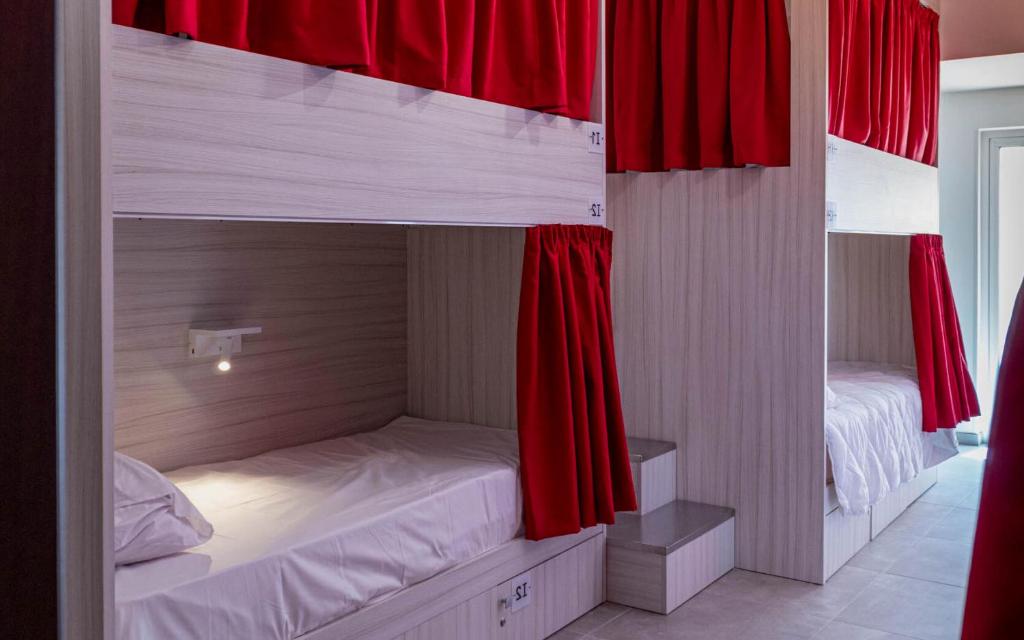 a bedroom with two bunk beds with red curtains at The Rose Hostel in St. Julianʼs