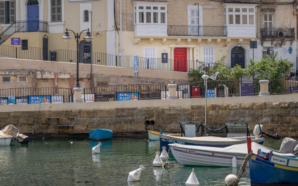 a group of boats in the water next to buildings at The Rose Hostel in St. Julianʼs