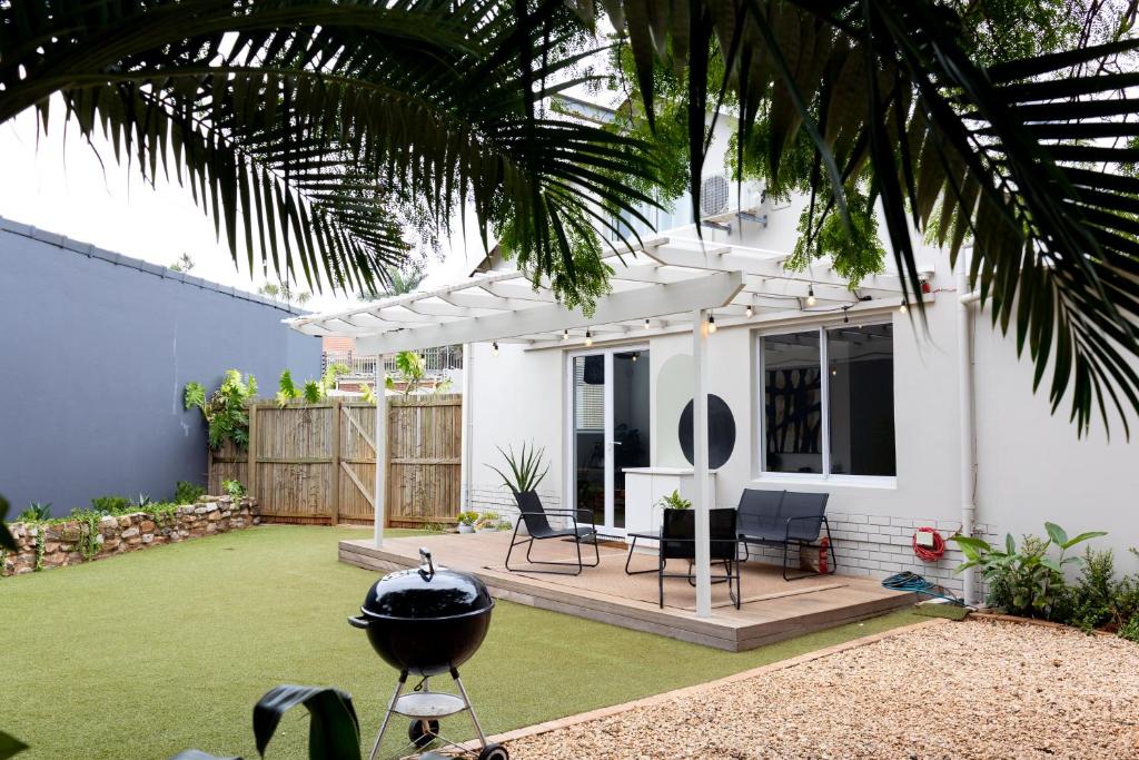a backyard with a grill and a house at Peaceful Modern Home with Private Garden in Durban North in Durban