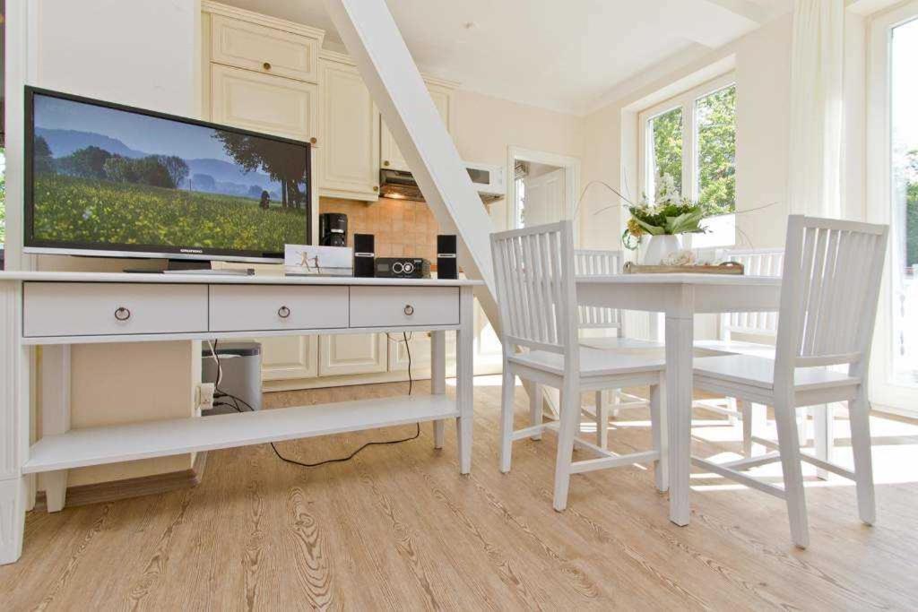 una sala da pranzo bianca con TV, tavolo e sedie di Villa Amelia App 12 a Heringsdorf