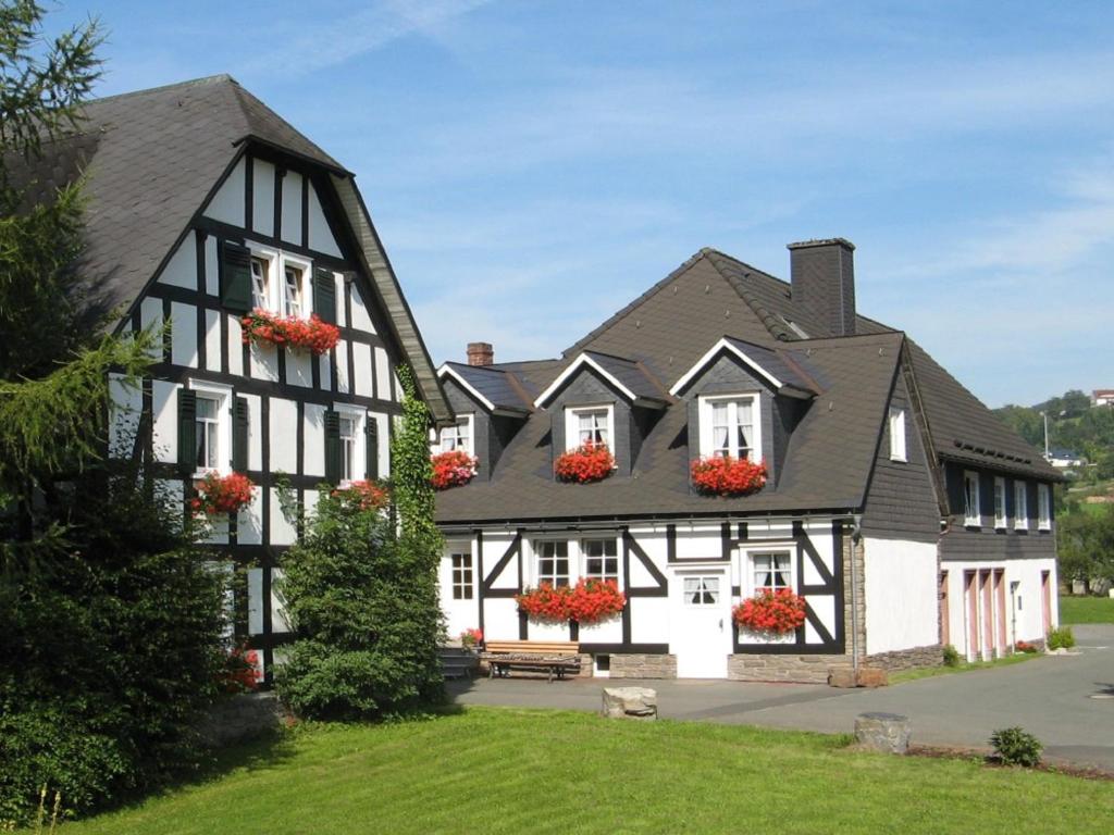 ein schwarzweißes Gebäude mit Blumenkästen an den Fenstern in der Unterkunft Gästehaus Schwarzenauer Mühle in Bad Berleburg