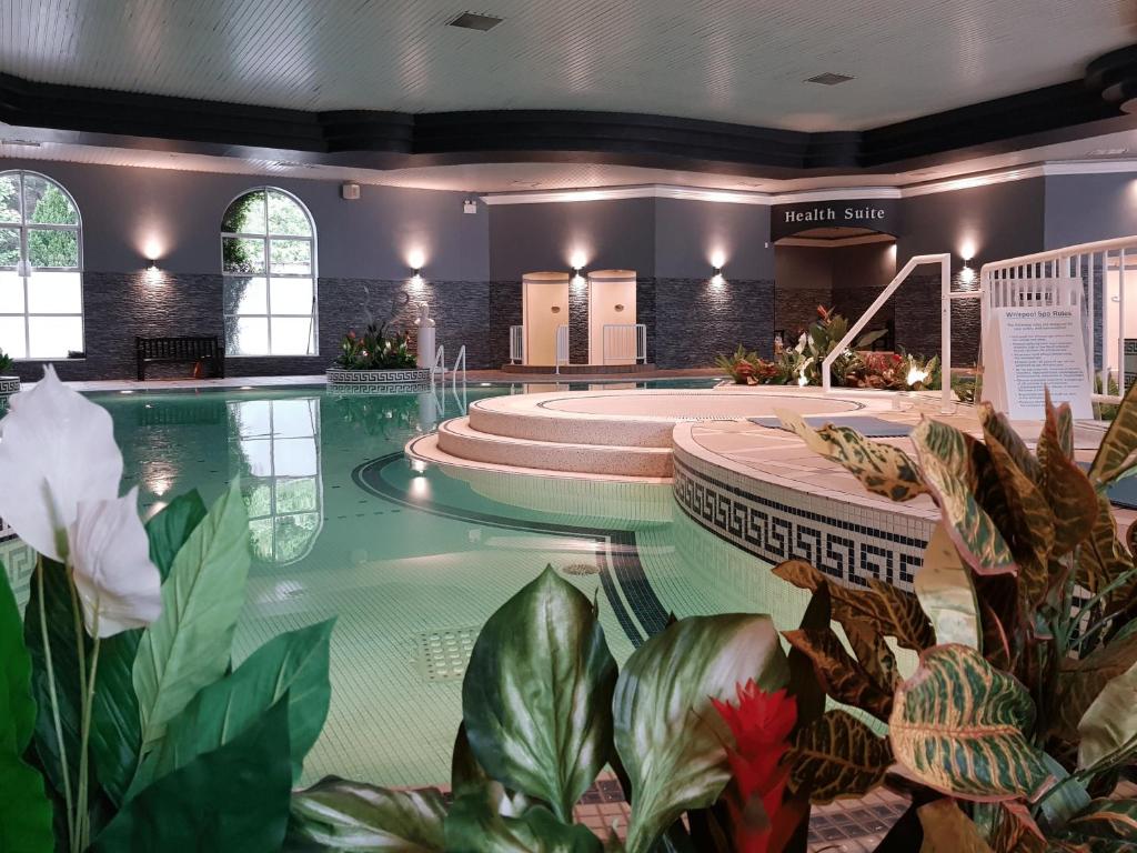 a swimming pool with plants in a building at Rochestown Park Hotel in Cork