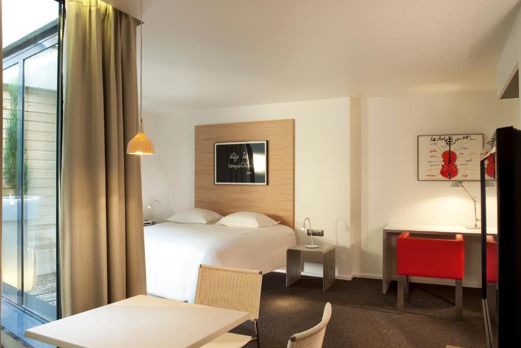a hotel room with a bed and a desk at Hotel Le Pavillon 7 in Obernai