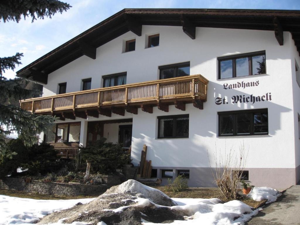 - un grand bâtiment blanc avec un balcon en bois dans l'établissement Apartment Michaeli, à Pettneu am Arlberg