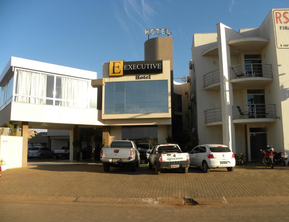 um parque de estacionamento com carros estacionados em frente a um edifício em Executive Hotel em Lucas do Rio Verde