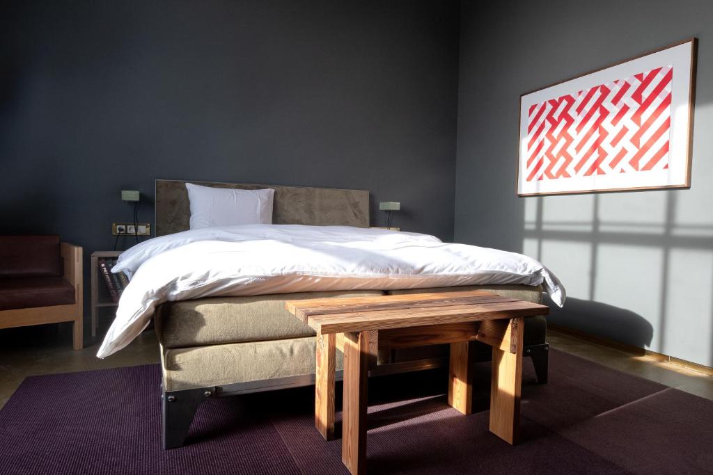 een slaapkamer met een bed en een houten tafel bij Hotel Piet Hein Eek in Eindhoven