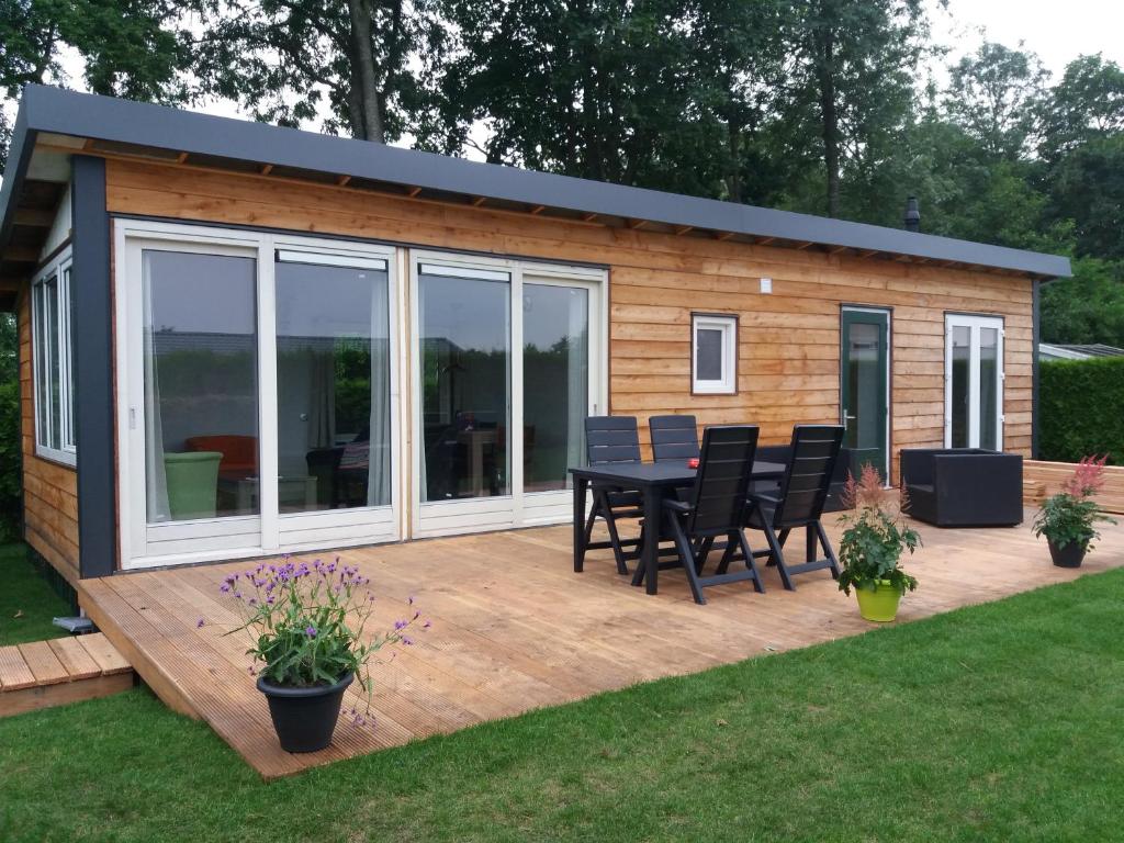 Luxe bungalow op rustig vakantiepark. في Dronrijp: كابينة على طاولة وكراسي على سطح السفينة