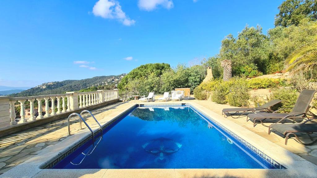 einen Pool mit zwei Gartenstühlen und einem Pool in der Unterkunft Villa Majestic in Lloret de Mar