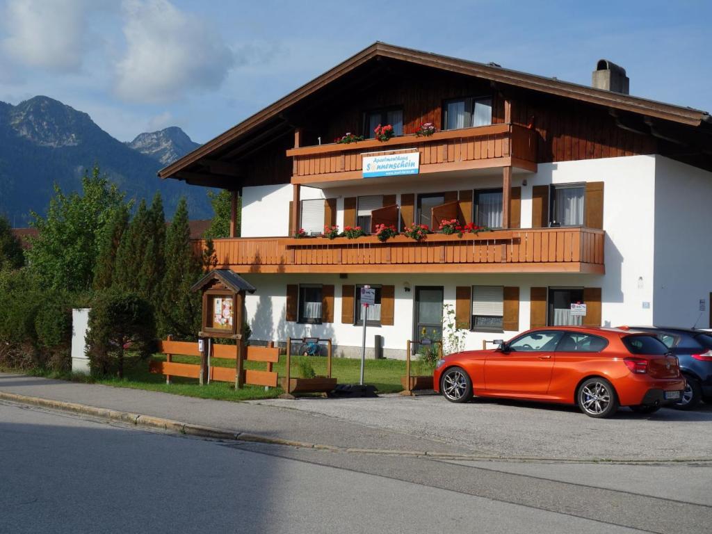 un coche rojo estacionado frente a un edificio en Apartmenthaus Sonnenschein - Chiemgau Karte, en Inzell