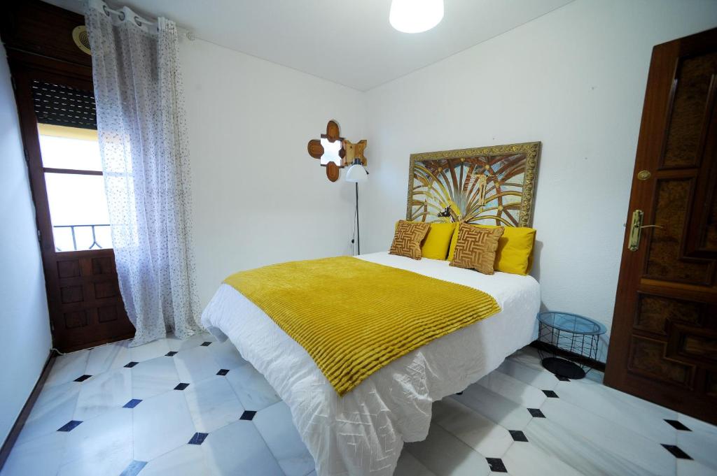1 dormitorio con 1 cama con manta amarilla en San Basilio´s Red House, en Córdoba