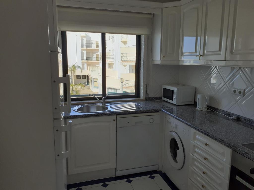 a white kitchen with a sink and a window at Clube Meia Praia in Lagos